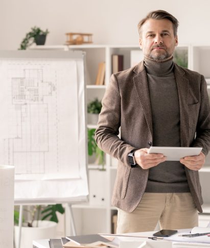 architect-with-tablet-standing-by-desk-on-backgrou-2023-11-27-04-48-52-utc.jpg